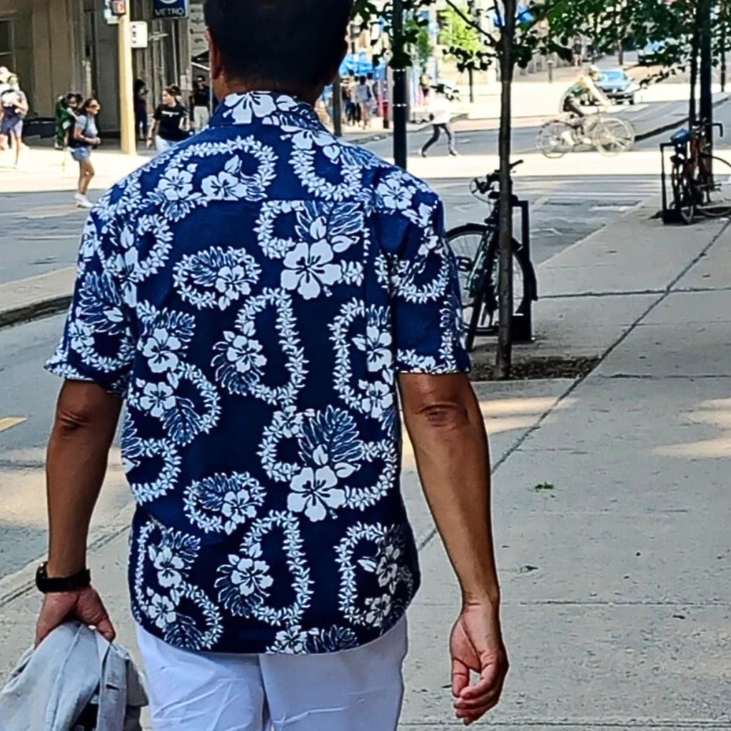 Homme portant une chemise tahitienne bleue à motifs fleuris blancs en ville, Tahiti Tropic