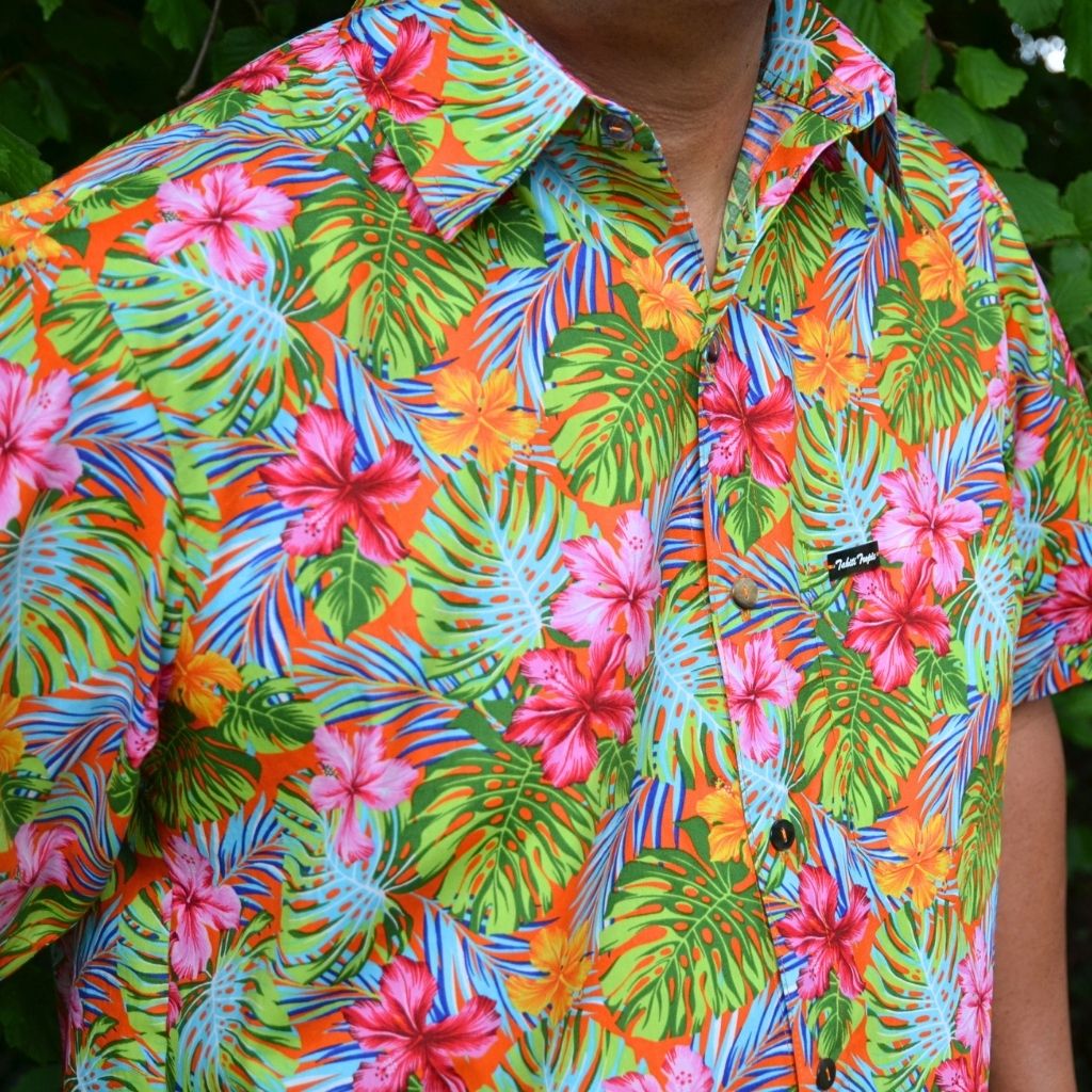 Chemise tahitienne Taaroa corail hibiscus rose et orange sur fond orange. Chemise en coton manches courtes, tissu tahitien et boutons en nacre. Edition limitée