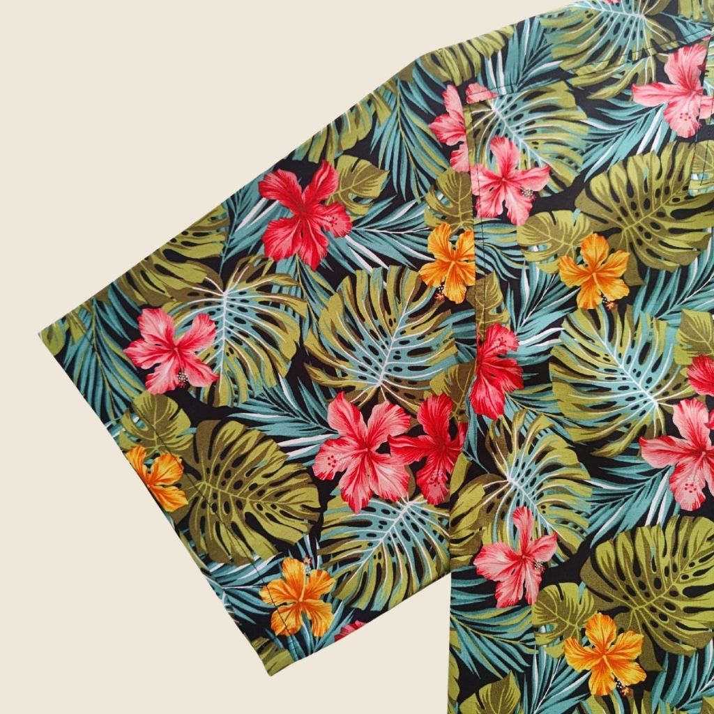 Chemise tahitienne hibiscus rose et orange sur fond noir. Chemise en coton manches courtes, vue de la manche, en tissu tahitien et boutons en nacre. Edition limitée