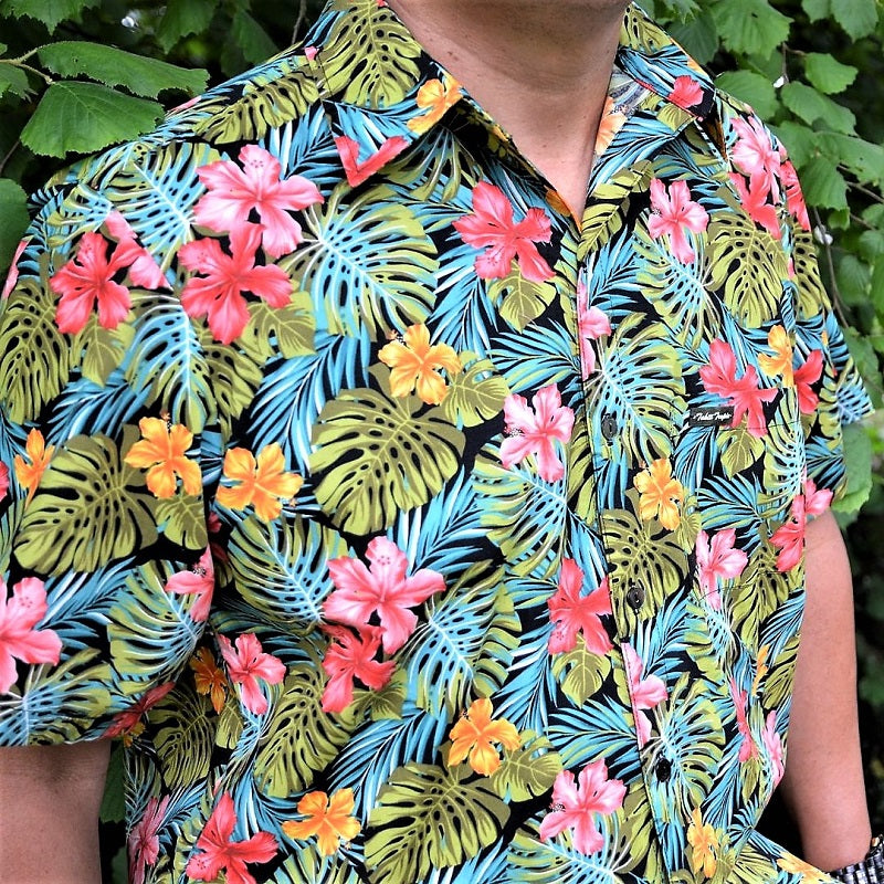 Chemise tahitienne hibiscus rose et jaune sur fond noir. Chemise en coton manches courtes, détails du tissu tahitien et boutons en nacre. Edition limitée