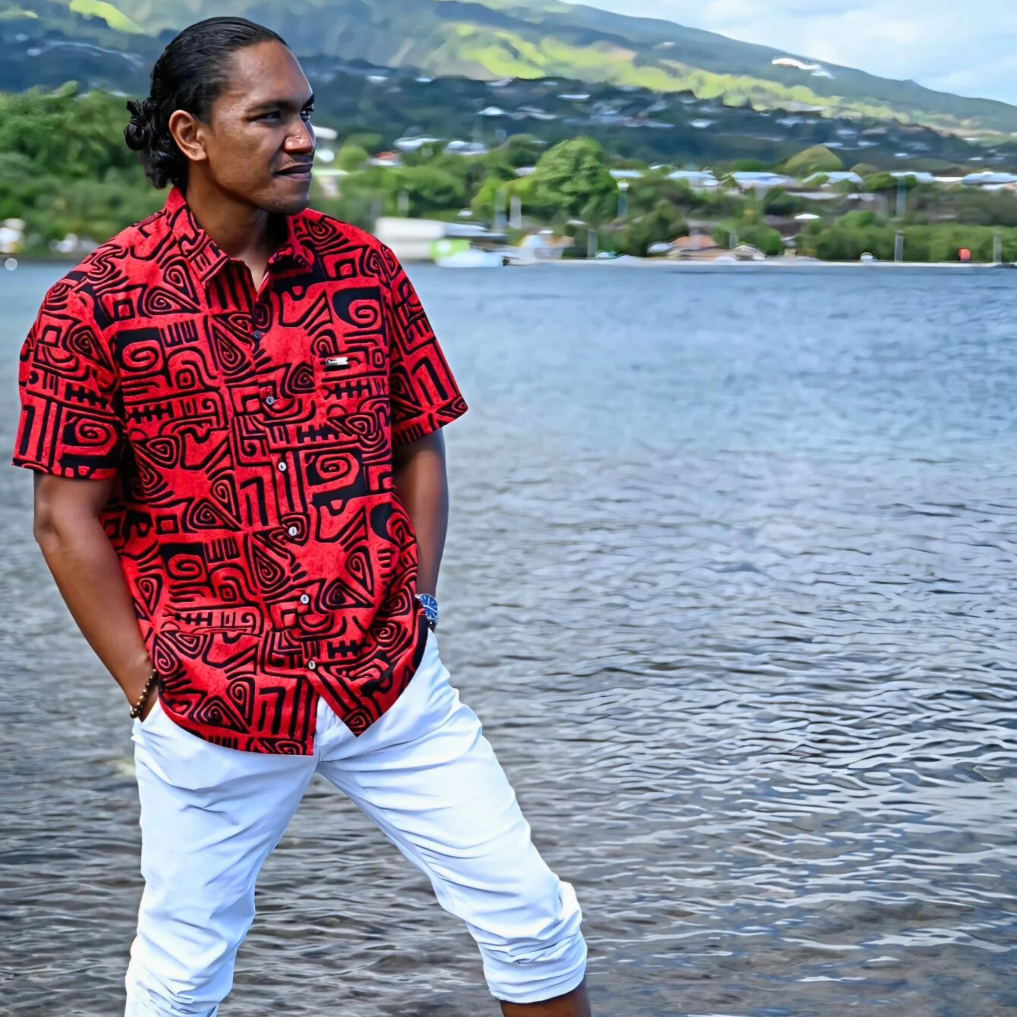 Homme portant une chemise tahitienne rouge à motifs tatouages polynésiens en bord de mer à Tahiti.